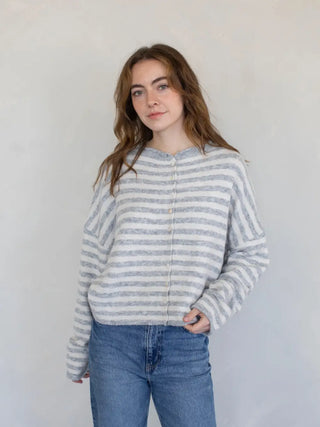 Woman wearing a striped sweater and jeans against a plain background