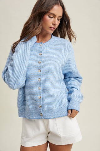 Woman wearing a blue striped cardigan with button details on a beige background