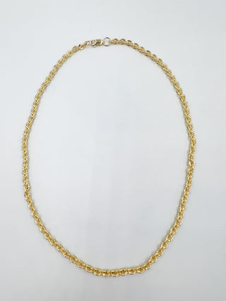Gold chain necklace on a light gray background