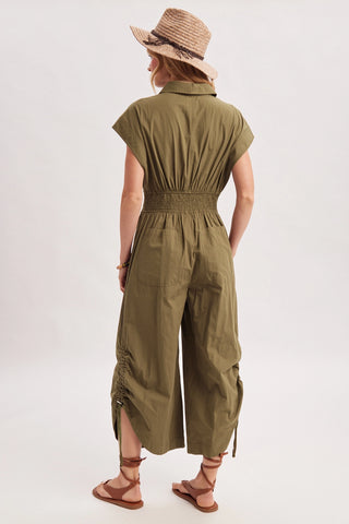 Person wearing a green jumpsuit and straw hat on a white background