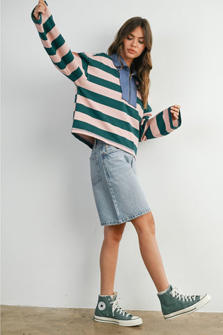 Woman wearing a striped sweater, denim skirt, and Converse shoes against a white background