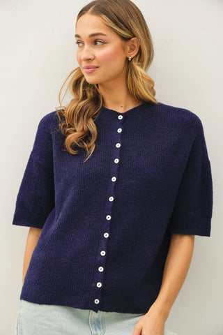 Women wearing a navy short sleeve cardigan against a neutral background. 
