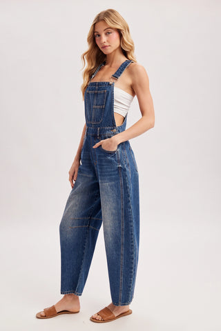 Woman wearing blue denim overalls on a white background