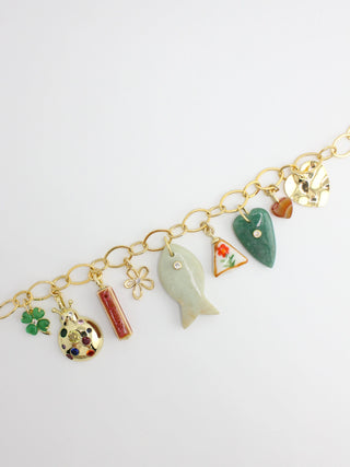 Gold bracelet with various charms on a white background