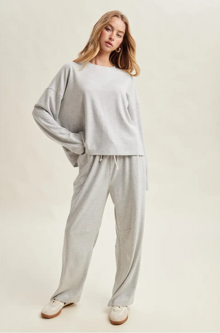Woman wearing a light gray loungewear set on a plain background