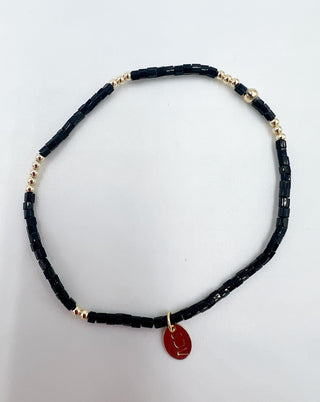 Necklace with black beads and a red pendant on a white background
