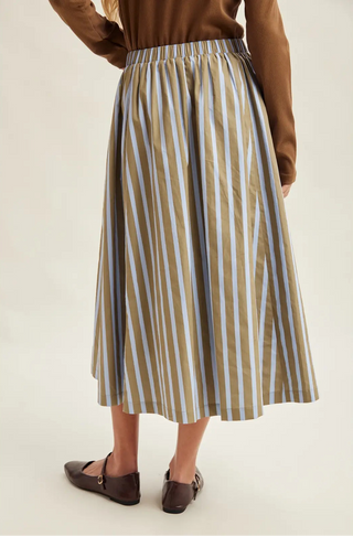 A women wearing a striped skirt against a neutral background.