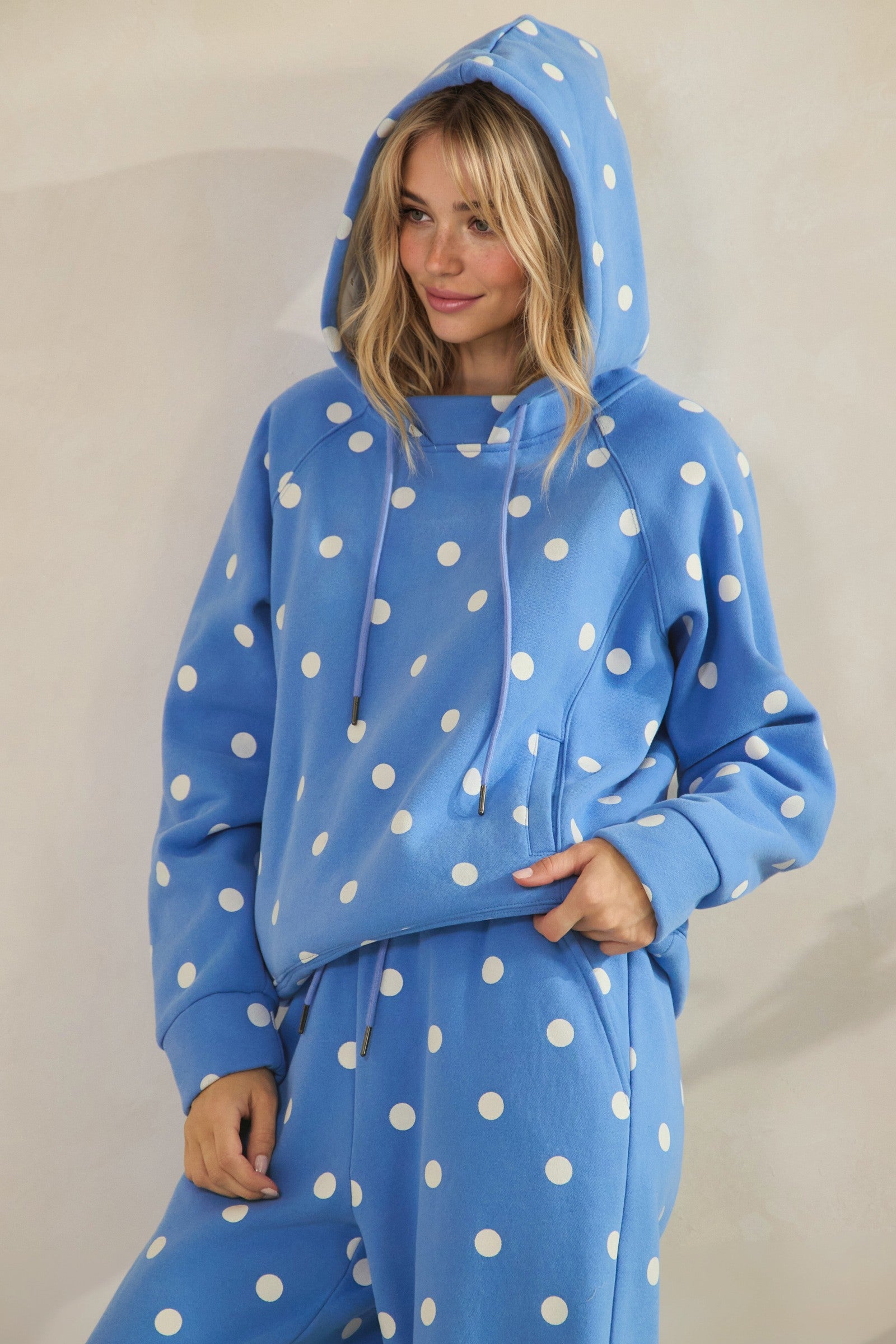 Person wearing a blue polka dot hoodie and pants against a plain background