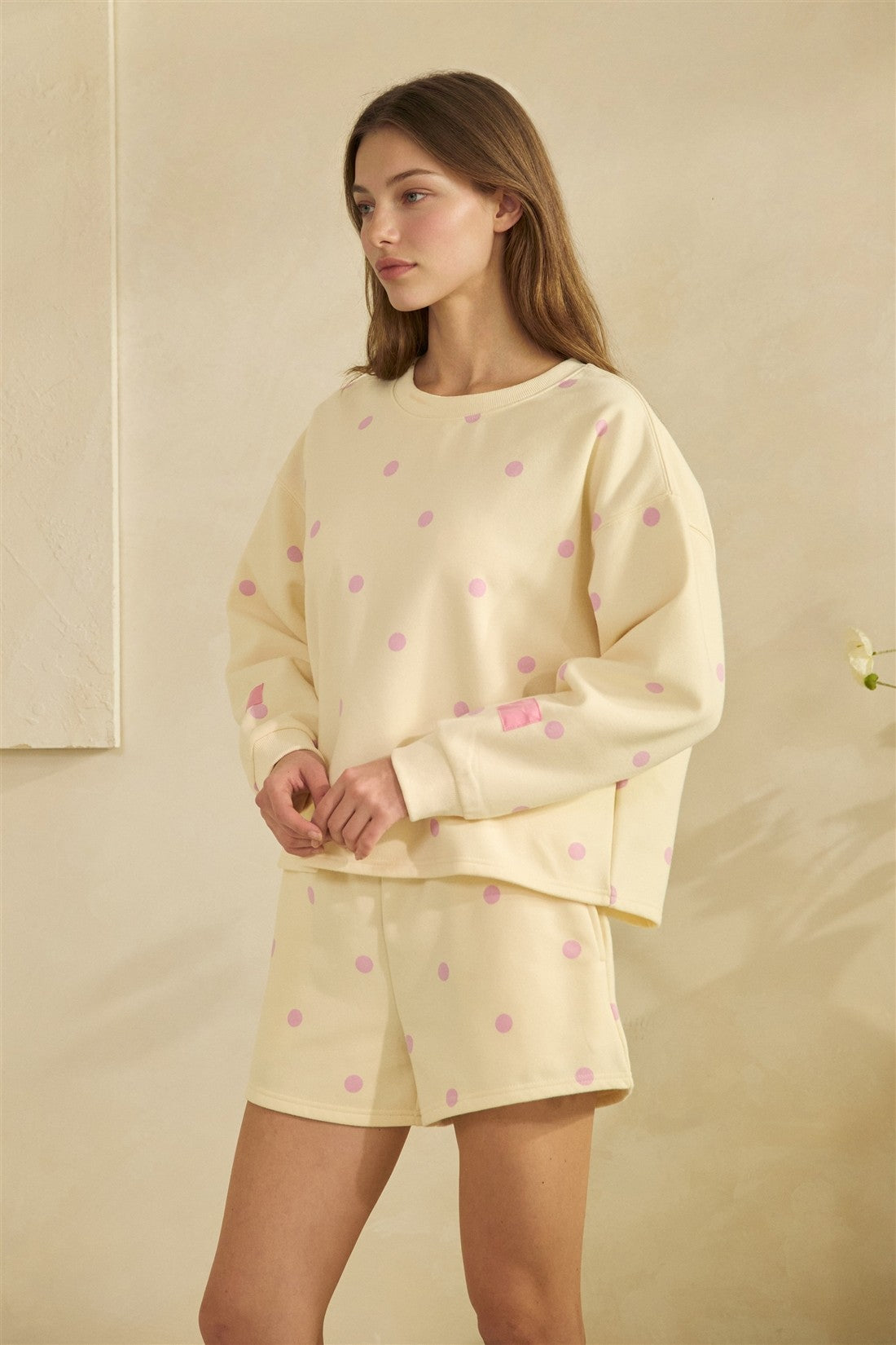 Woman wearing a yellow outfit with pink polka dots on a beige background
