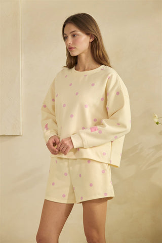 Woman wearing a yellow outfit with pink polka dots on a beige background