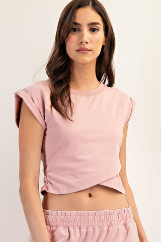 Woman wearing a pink sleeveless top and shorts against a white background