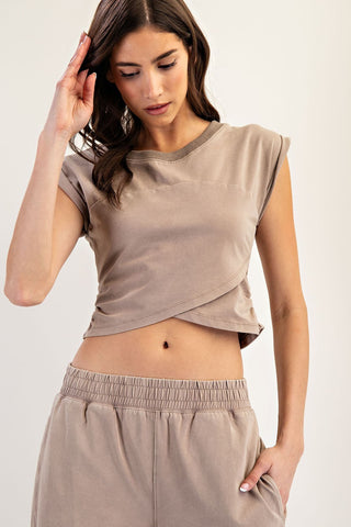 Woman wearing a beige sleeveless top and pants against a plain background