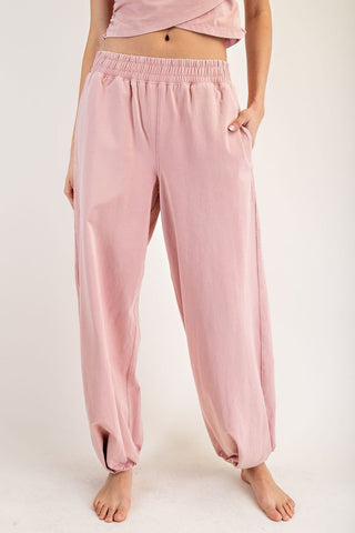 Pink pajama pants worn by a person on a white background