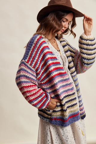 Woman wearing a colorful striped sweater and brown hat against a neutral background