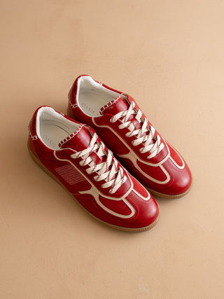 Red sneakers with white laces on a beige background