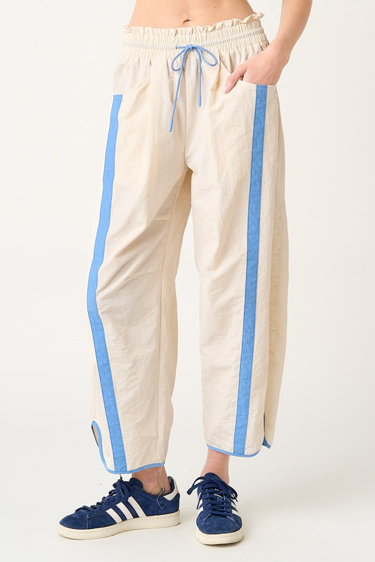 Beige pants with blue stripes worn by a person on a white background