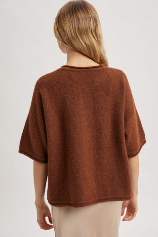 Woman wearing a brown poncho against a white background