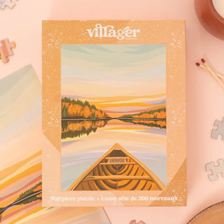 Villager puzzle box with a scenic illustration of a lake and canoe on a pink background.