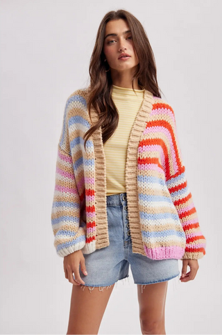 Woman wearing a colorful striped cardigan on a plain background