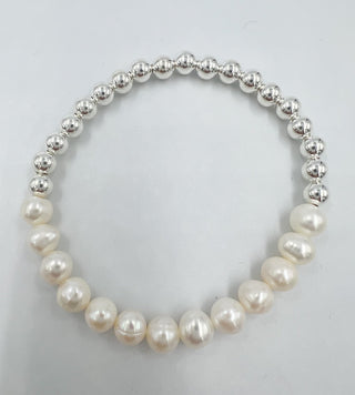 a beaded bracelet with half pearls and half silver beads on a table