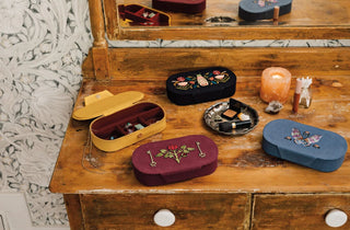 A nightstand set up with multiple coloured jewelry boxes 