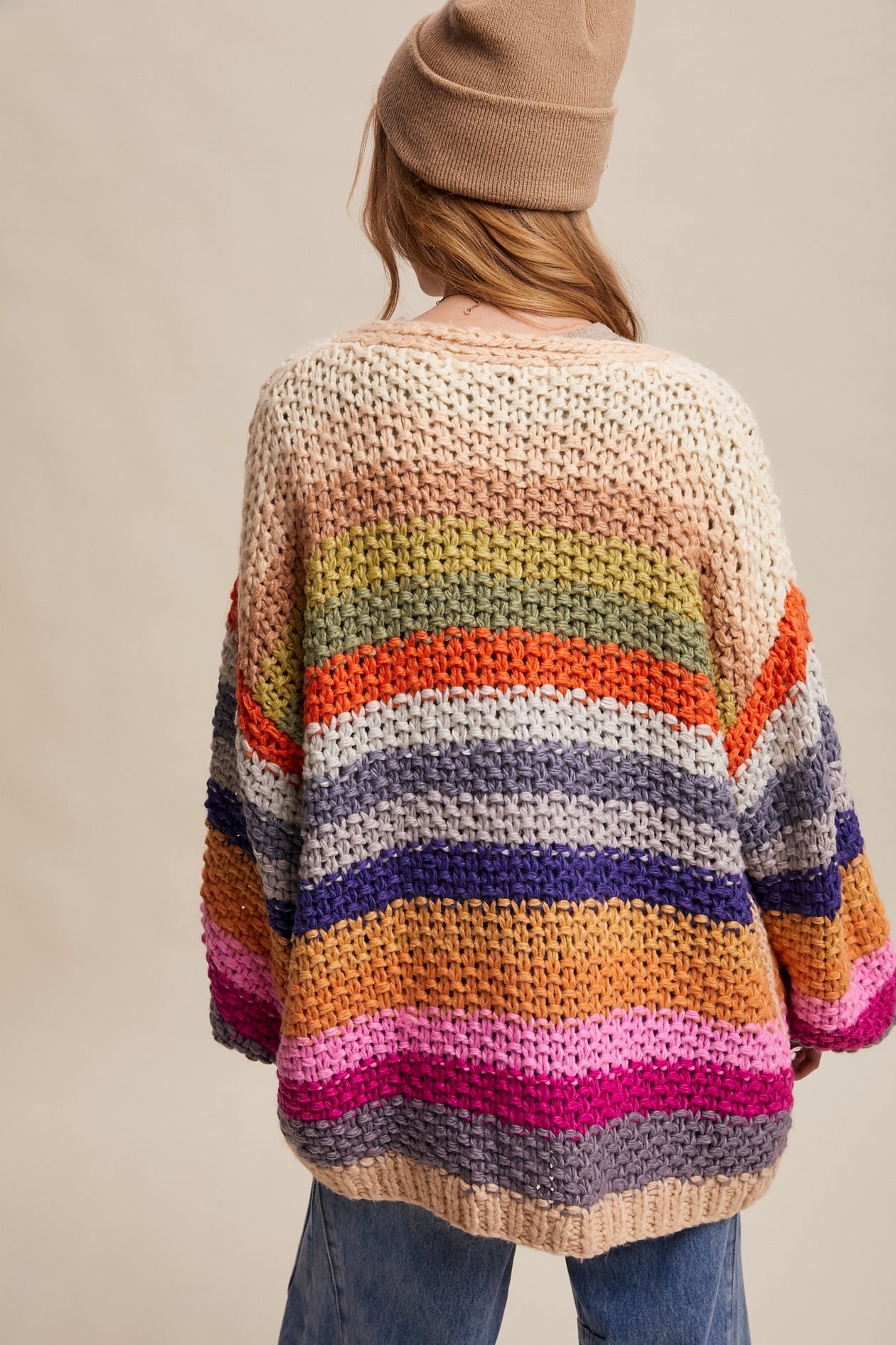 Person wearing a colorful striped sweater with a neutral background