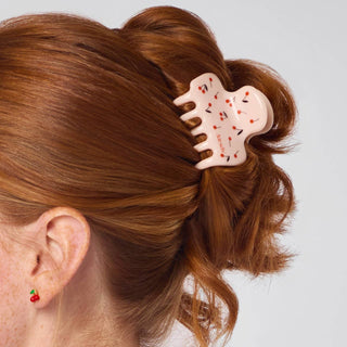 Person with red hair wearing a decorative hair clip on a plain background