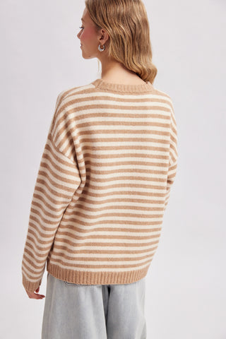 Women wearing a striped beige sweater against a neutral background.