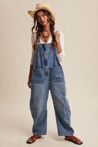 Woman wearing denim overalls and a straw hat on a beige background