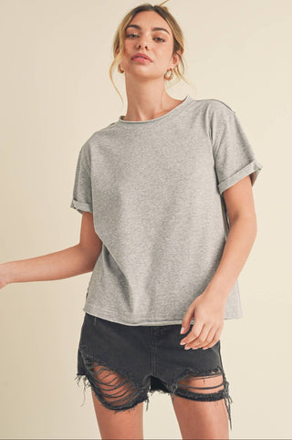 Woman wearing a gray oversized t-shirt and black shorts on a beige background