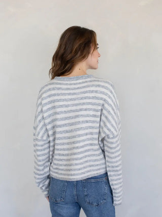 Woman wearing a striped sweater and jeans against a plain background