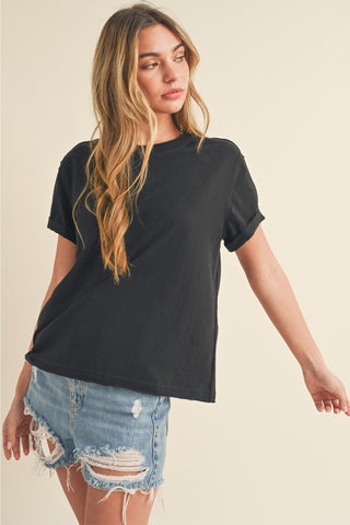 Woman wearing a black t-shirt and denim shorts on a beige background