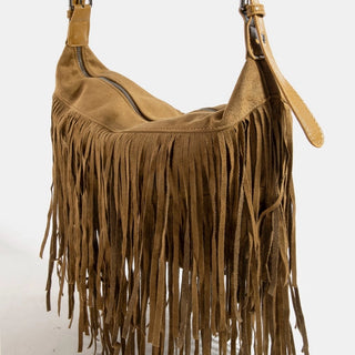 A brown suede fringe shoulder bag with a slouchy crescent shape, featuring a top zipper, a long hanging fringe, and a matching leather strap with a metal buckle, shown against a plain white background.