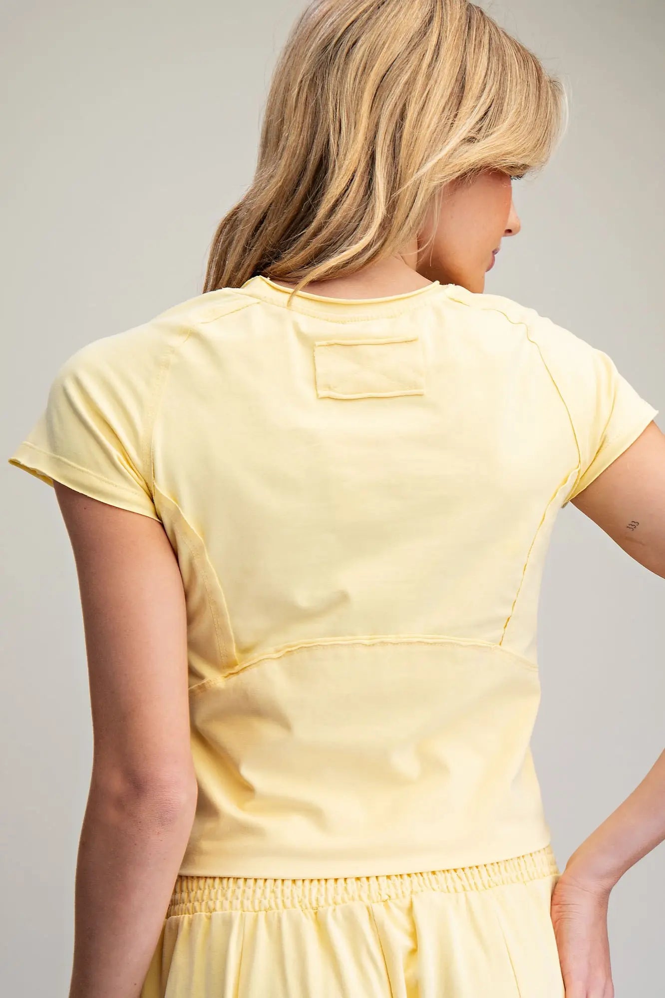 Woman wearing a yellow top and skirt against a plain background