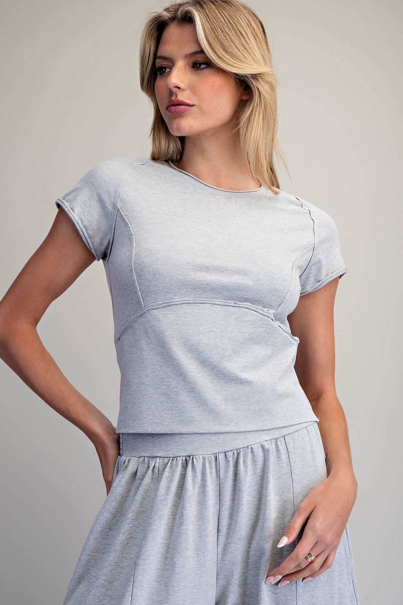 Woman wearing a light gray sweat set against a plain background