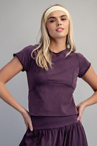Woman wearing a purple outfit with a headband against a gray background