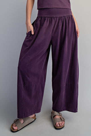 Person wearing purple wide-leg pants on a gray background