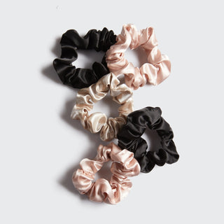 Set of black, beige, and pink scrunchies on a light gray background
