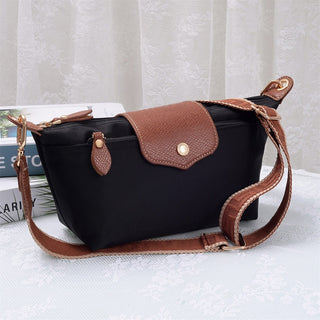 Black handbag with brown leather accents on a white surface