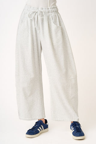 Person wearing light gray sweatpants and blue sneakers on a white background