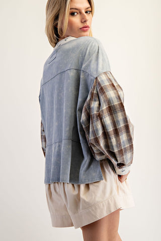 Woman wearing a denim and plaid shirt with a plain background