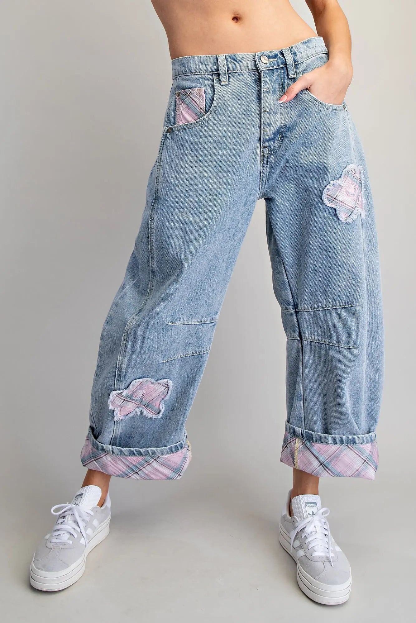 Denim pants with floral patches worn by a person on a plain background