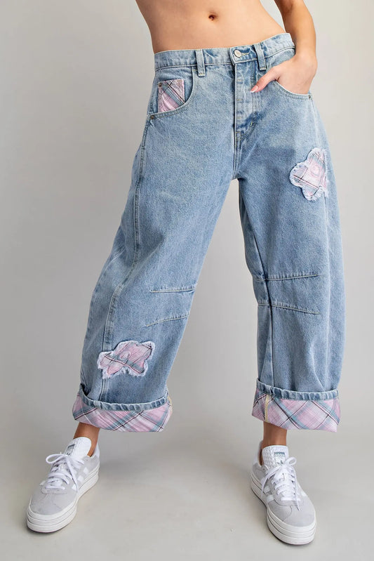 Denim pants with floral patches worn by a person on a plain background