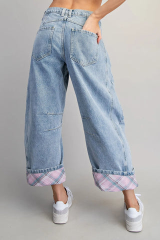 Light blue jeans with plaid cuffs worn by a person on a gray background