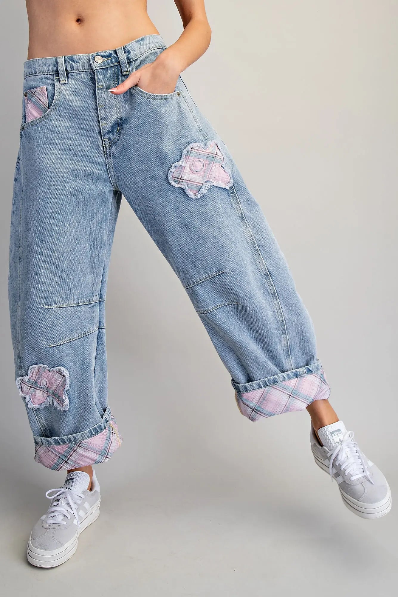 Denim jeans with floral patches worn by a person on a plain background