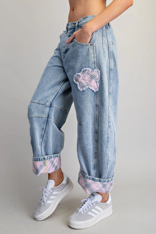 Person wearing light blue jeans with floral patches and white sneakers on a plain background