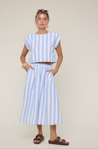 Woman wearing a blue and white striped outfit against a plain background