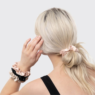 Woman with blonde hair tied in a ponytail wearing scrunchies on a light gray background