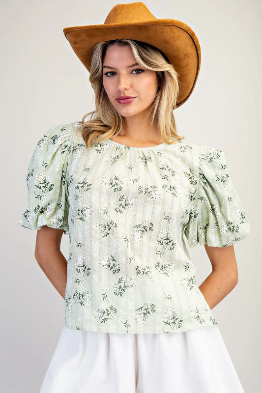 Women wearing a green floral blouse and a brown hat