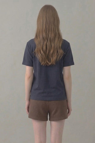 Person wearing a dark blue t-shirt and brown shorts against a plain background